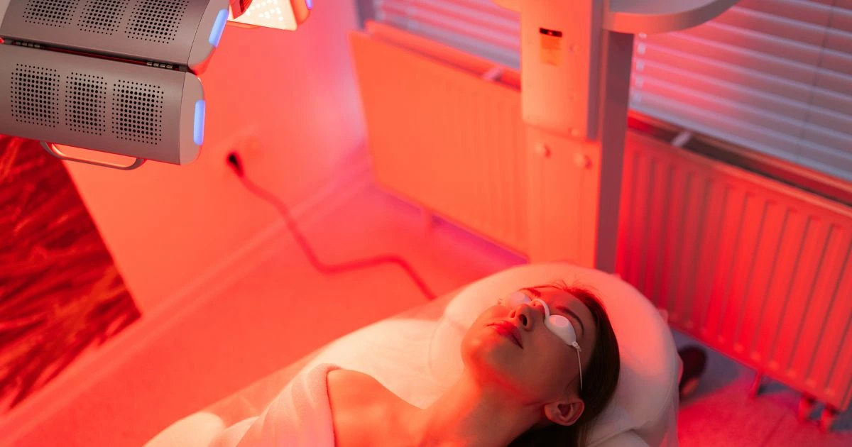 Woman touching her cheek, showing firm, youthful, and radiant skin achieved through collagen-boosting treatments like LED light Therapy.