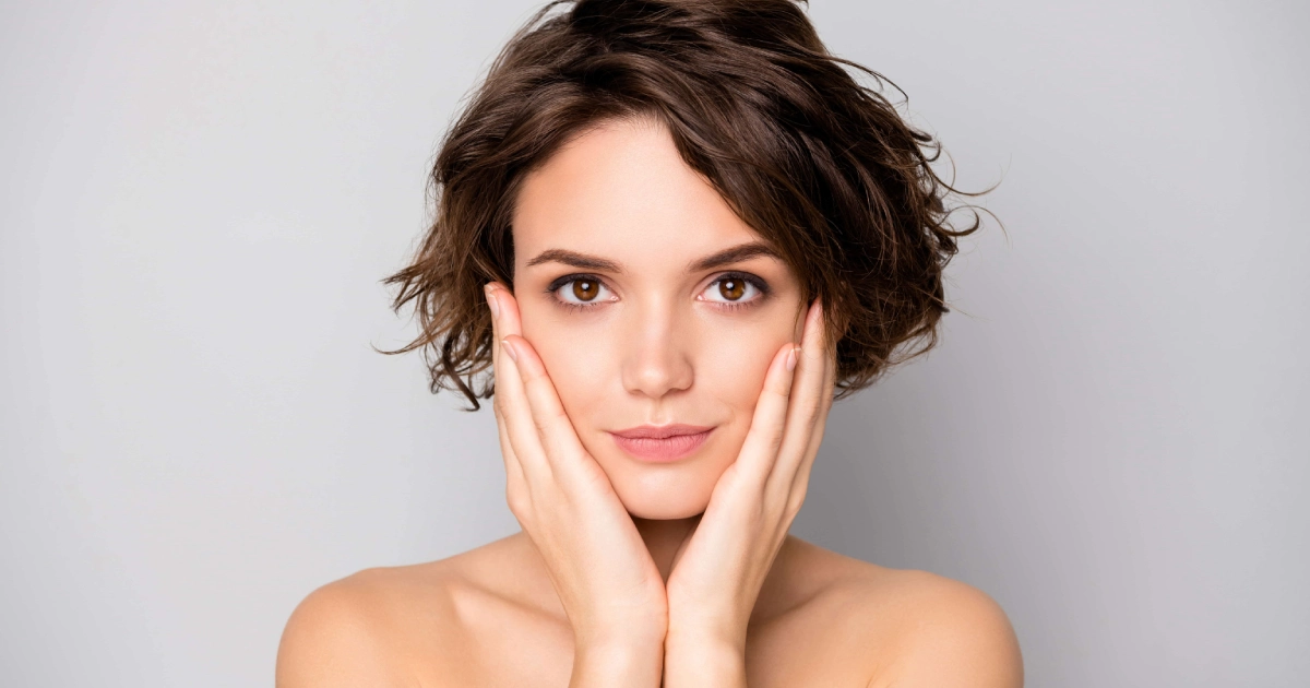 Young woman with short, wavy brown hair frames her face, featuring Morpheus8 in Morristown, TN, against a grey background.